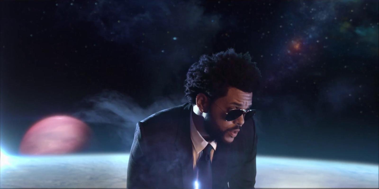 a man in a suit and tie standing in front of a planet
