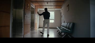 a man standing in a hallway next to a chair