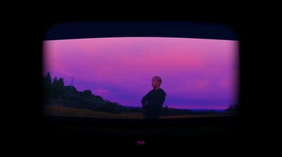a man standing in front of a purple sky
