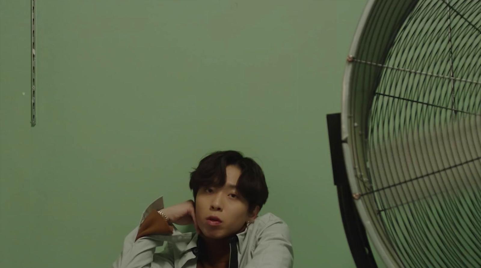 a young man sitting in front of a fan