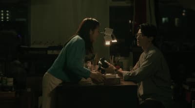 a woman handing a bottle of wine to another woman