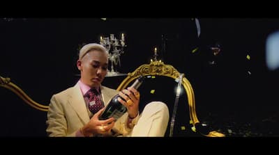 a man sitting on a chair holding a bottle of wine