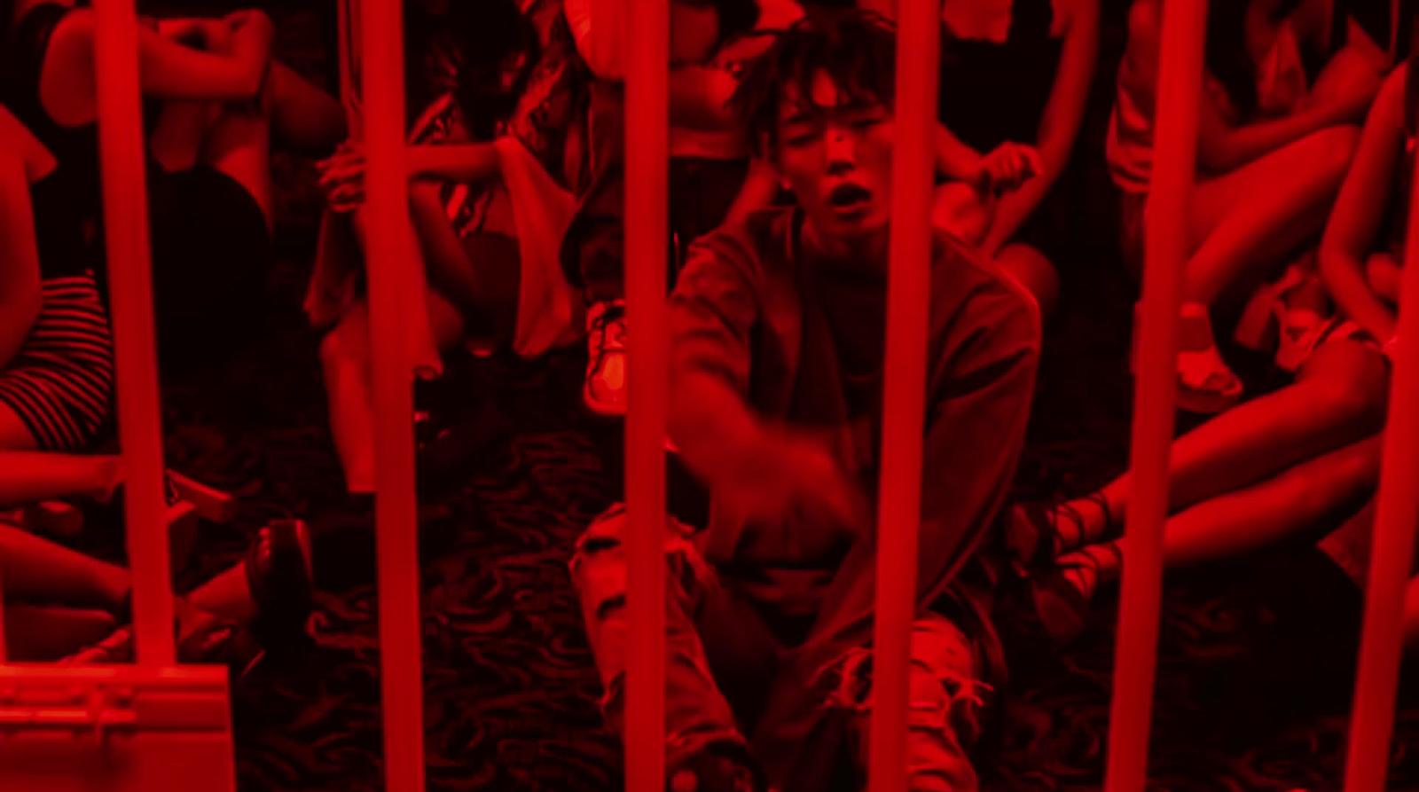 a man sitting in a jail cell with his hands on his knees