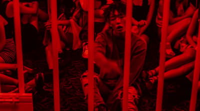 a man sitting in a jail cell with his hands on his knees