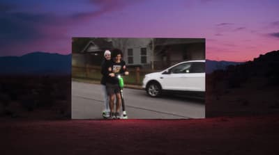 a couple of people riding scooters down a street