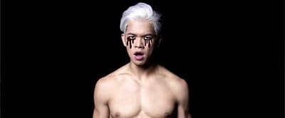 a shirtless man with white hair and dripping blood on his face