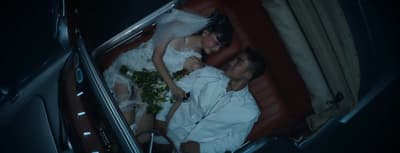 a bride and groom laying on a red couch