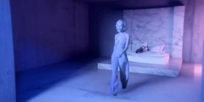 a woman standing next to a bed in a room