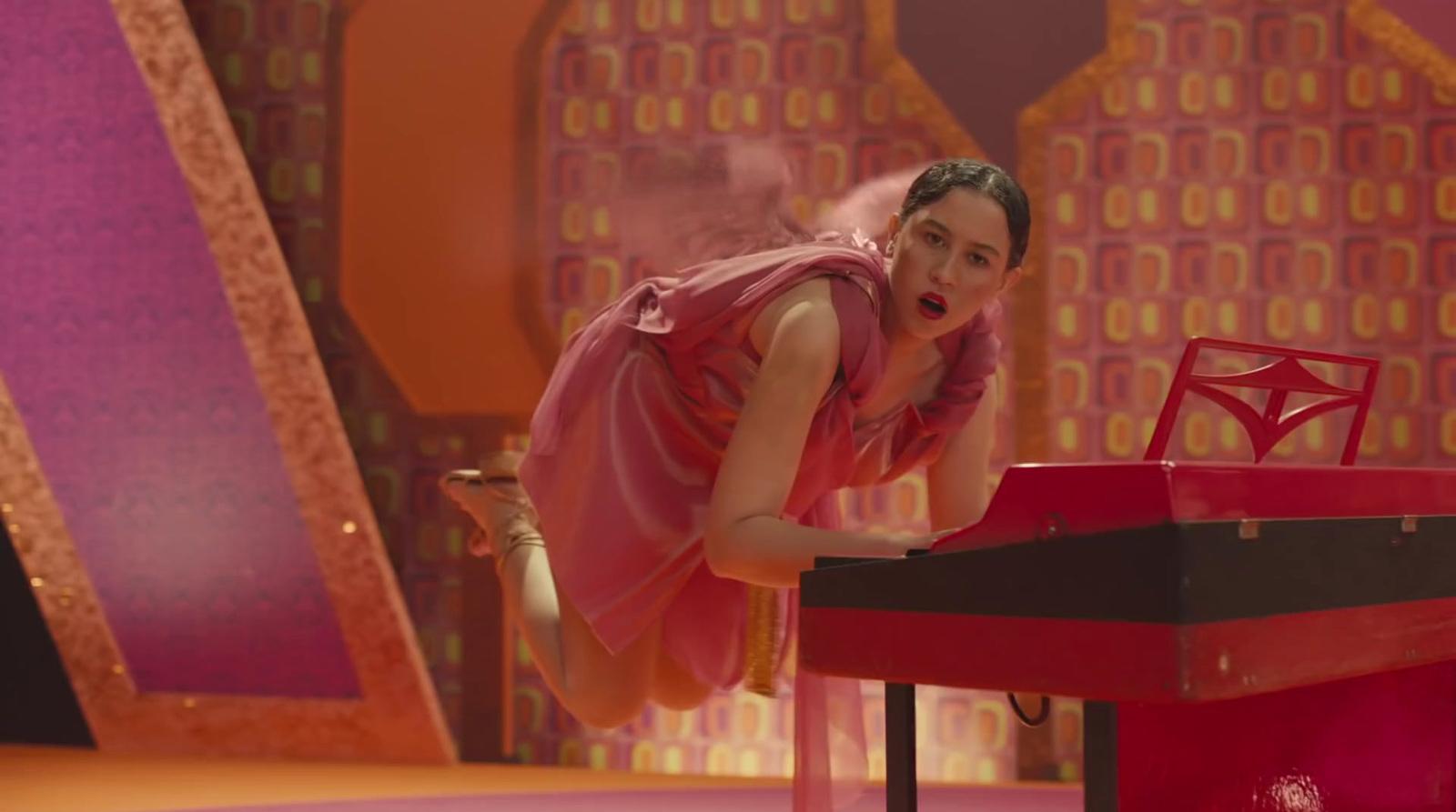 a woman in a pink dress leaning over a red table