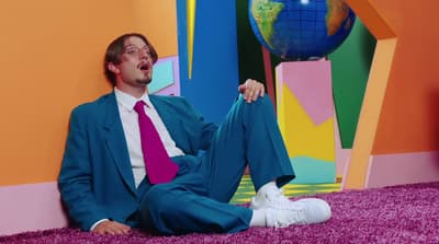 a man in a suit and tie sitting on the ground