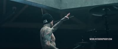 a man with a tattoo on his arm and a drum set in front of him