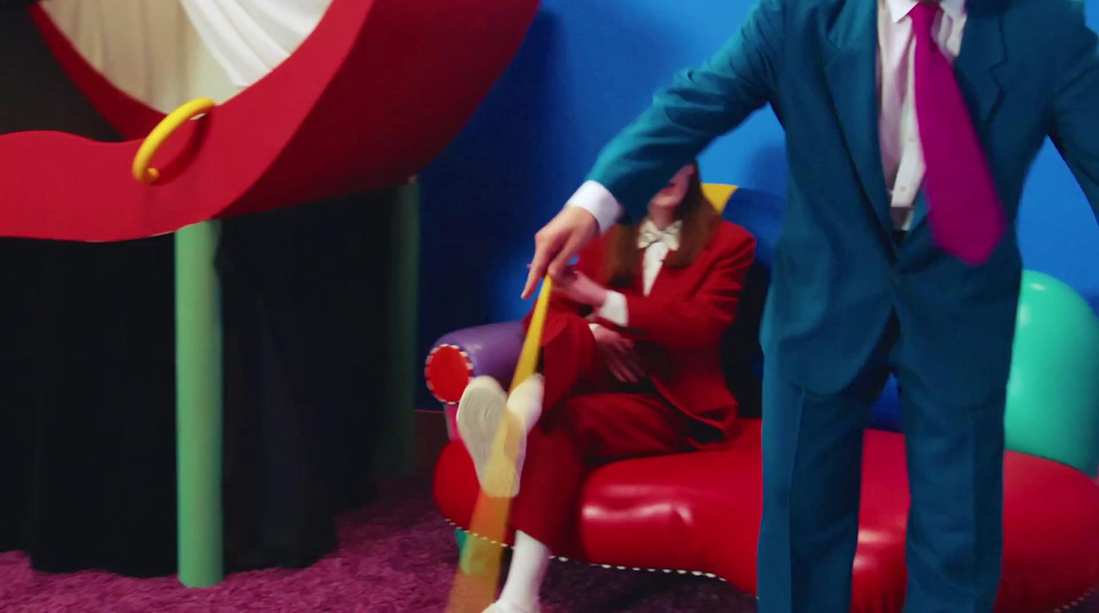 a man in a suit and tie standing next to a red chair