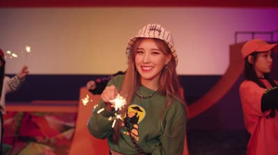 a woman in a green shirt holding sparklers