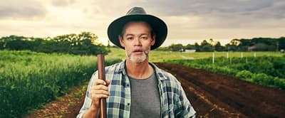 a man in a hat holding a stick in a field
