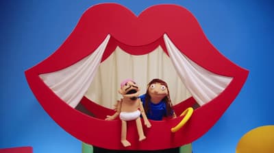 a couple of dolls sitting on top of a red couch