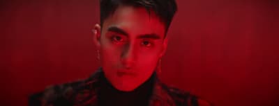 a man with dark hair and a red background