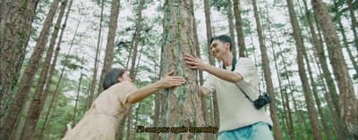 a man and a woman standing in the middle of a forest