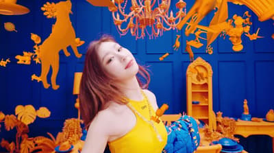 a woman in a yellow dress standing in front of a blue wall