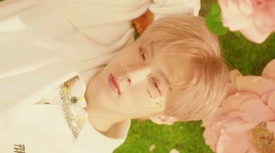 a young boy laying in the grass with flowers around him
