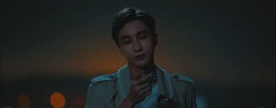 a man in a trench coat standing in a dark room