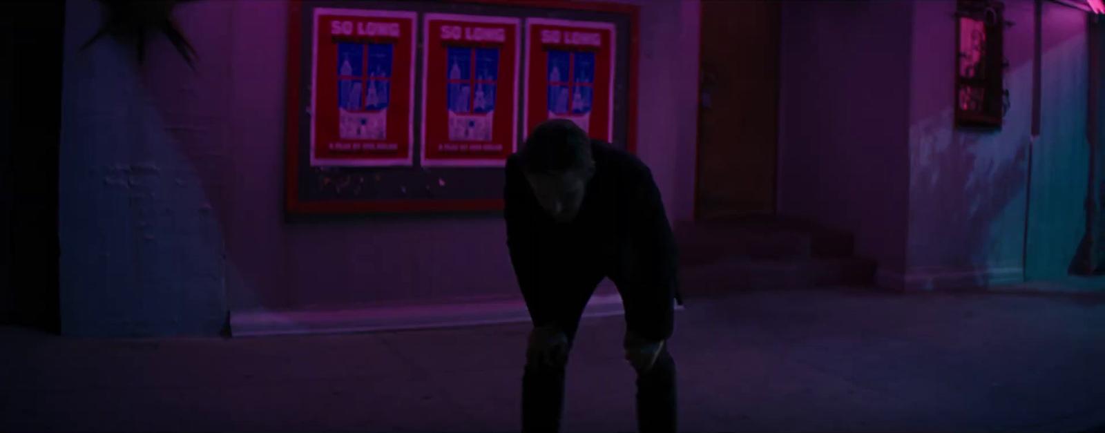a man standing in a dark alley with his back to the camera