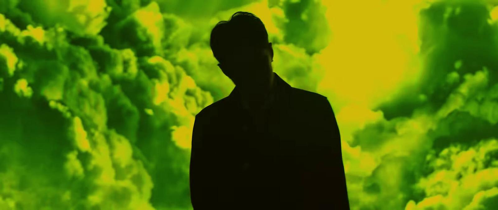 a man standing in front of a green and yellow background