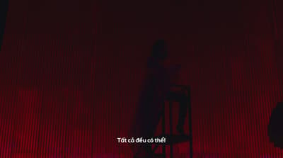 a person sitting on a chair in front of a red curtain