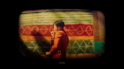 a young boy standing in front of a colorful wall