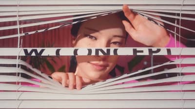 a woman looking through a window with blinds