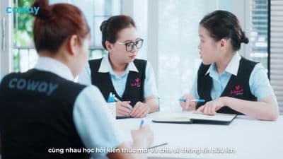 two women sitting at a table with a notebook and pen