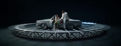 a man and a woman standing on top of a car