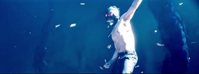 a shirtless man standing in front of a black wall