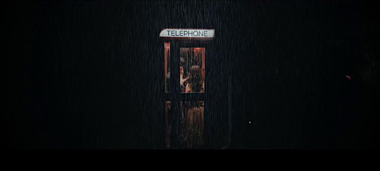 a telephone booth in the rain with a sign on it