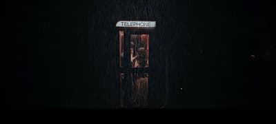 a telephone booth in the rain with a sign on it