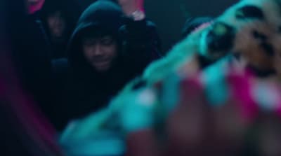 a man in a hoodie looking at himself in a mirror