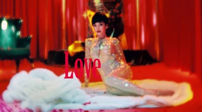 a woman sitting on top of a bed in front of a red curtain