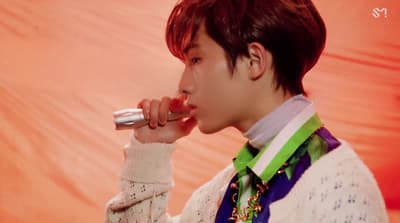 a man in a white sweater is holding a microphone