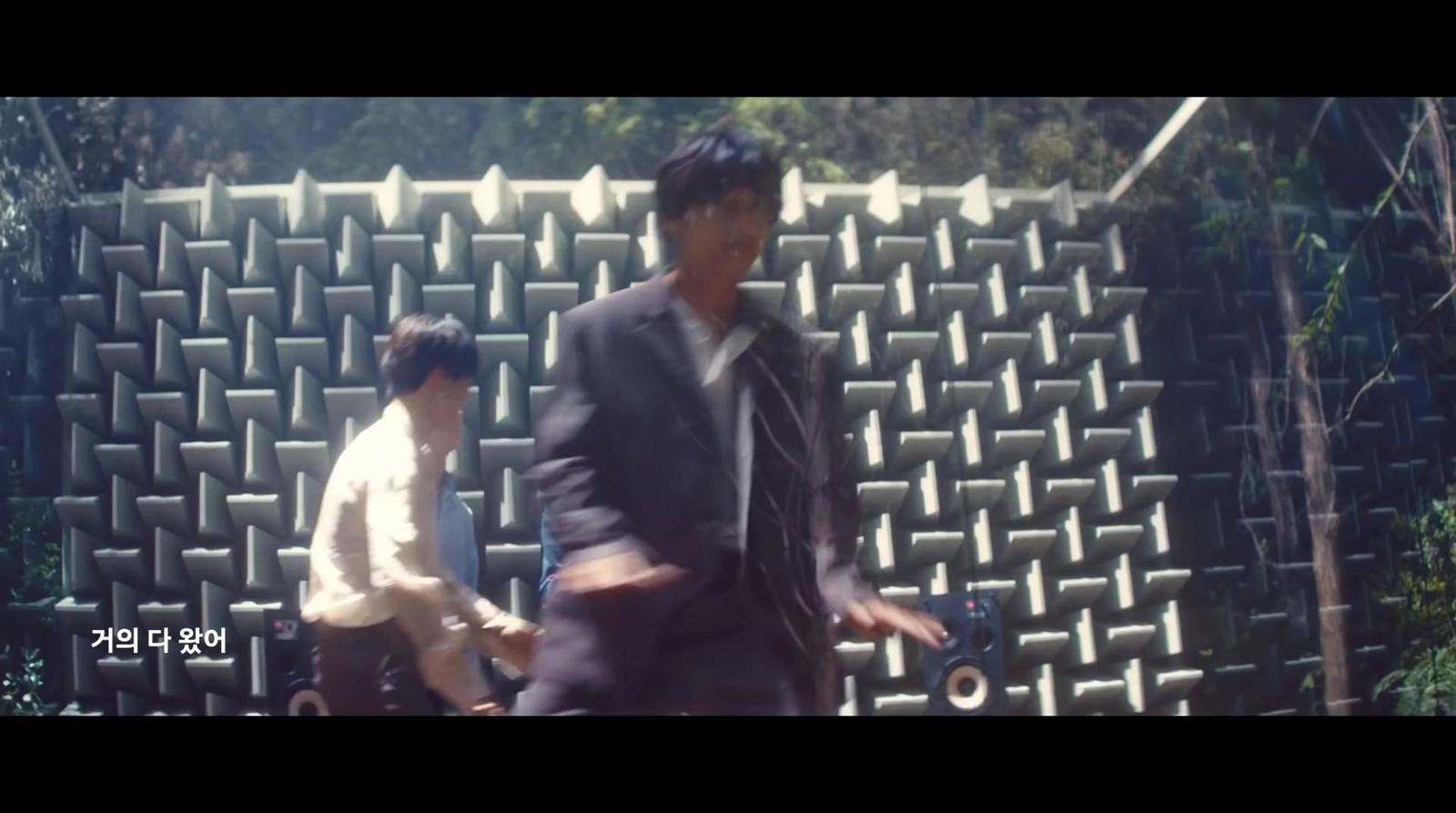 a man in a suit and tie walking by a wall