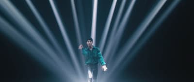 a man standing on a stage with a lot of lights behind him
