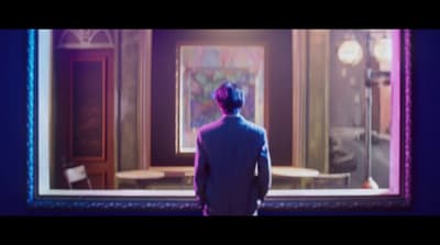 a man standing in front of a painting in a room