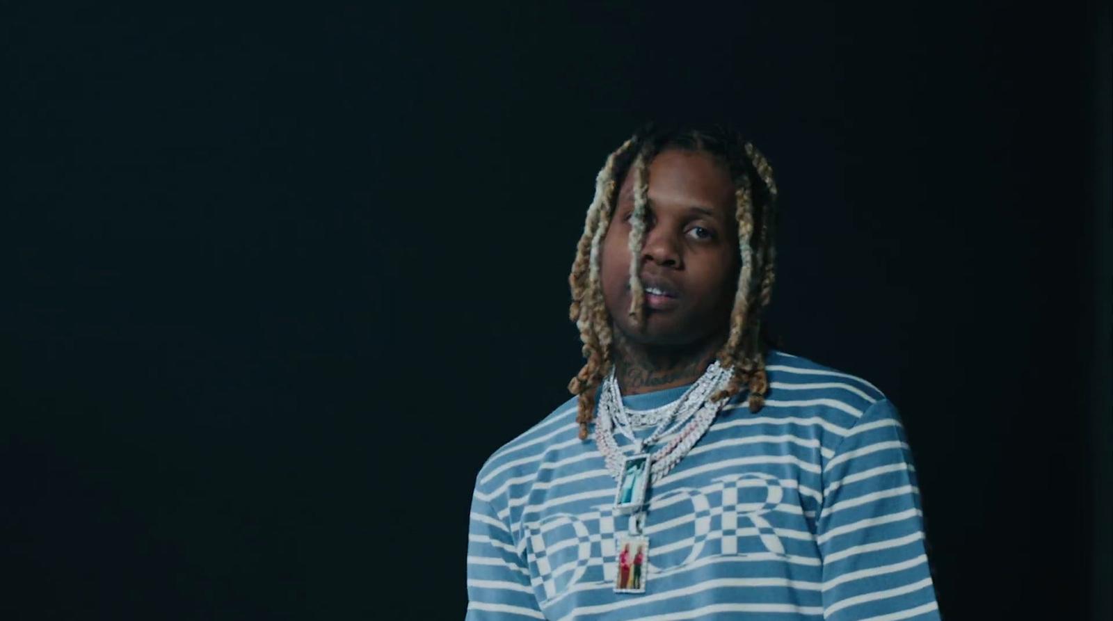 a man with dreadlocks standing in front of a black background