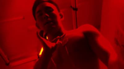 a man standing in a bathroom with a red light