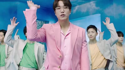 a man in a pink suit standing in front of a group of people