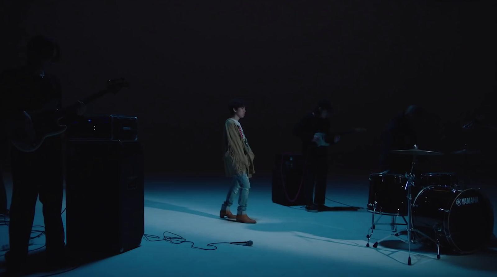 a man standing in front of a microphone in a dark room