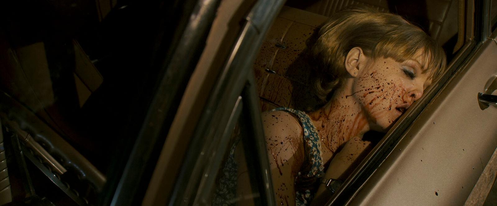 a woman with blood on her face sitting in a car