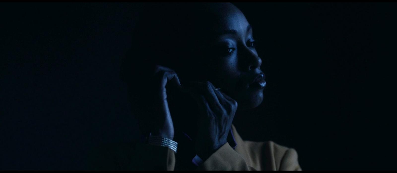 a woman in a dark room holding her hand up to her face