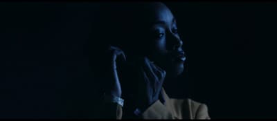 a woman in a dark room holding her hand up to her face