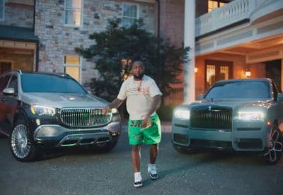 a man standing next to two cars in front of a building