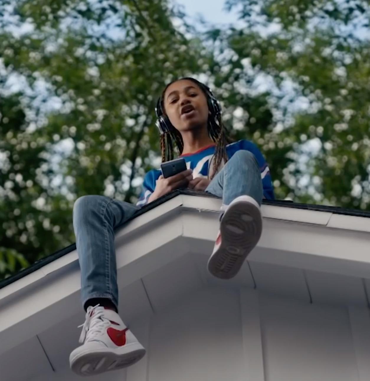 a woman sitting on top of a roof using a cell phone