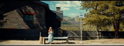a woman sitting on a bench in front of a building